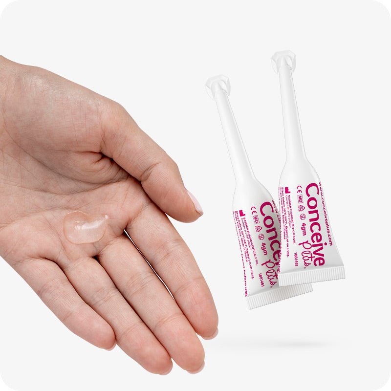 For Conceive Plus Max Combo - Fertility Lubricant Bundle (PT), two single-use 4g pre-filled fertility lubricant applicators placed next to an open hand with a clear drop of lubricant gel, demonstrating product texture and applicator size on a white background.